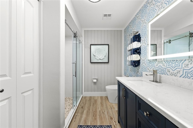 bathroom with vanity, hardwood / wood-style flooring, a shower with door, and toilet