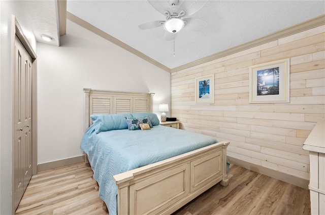 bedroom featuring vaulted ceiling, light hardwood / wood-style floors, ceiling fan, and wood walls