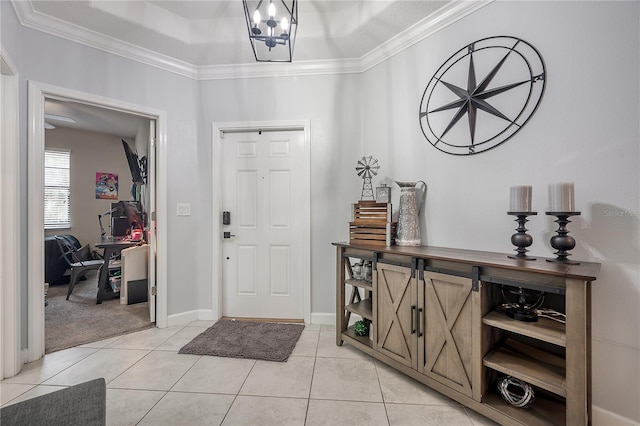 tiled entryway with an inviting chandelier, ornamental molding, and a raised ceiling