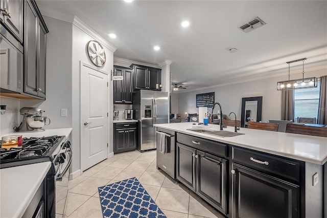 kitchen with sink, light tile patterned floors, appliances with stainless steel finishes, a kitchen island with sink, and ornamental molding