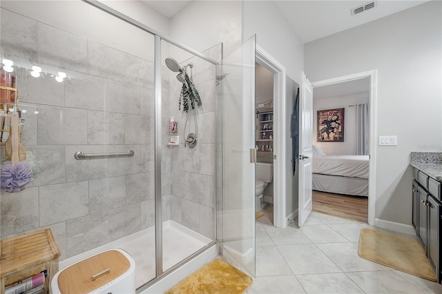 bathroom with tile patterned flooring, an enclosed shower, vanity, and toilet