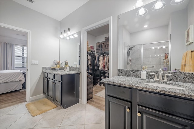 bathroom with tile patterned flooring, vanity, and a shower with door