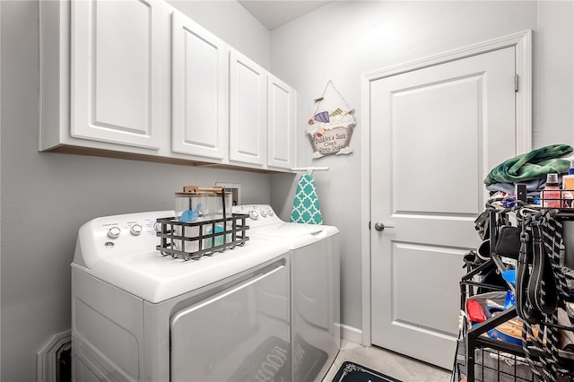 laundry room with light tile patterned flooring, cabinets, and washer and dryer