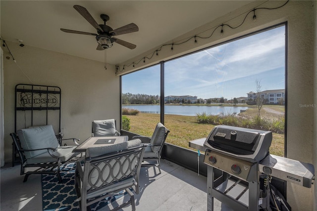 sunroom / solarium featuring ceiling fan and a water view