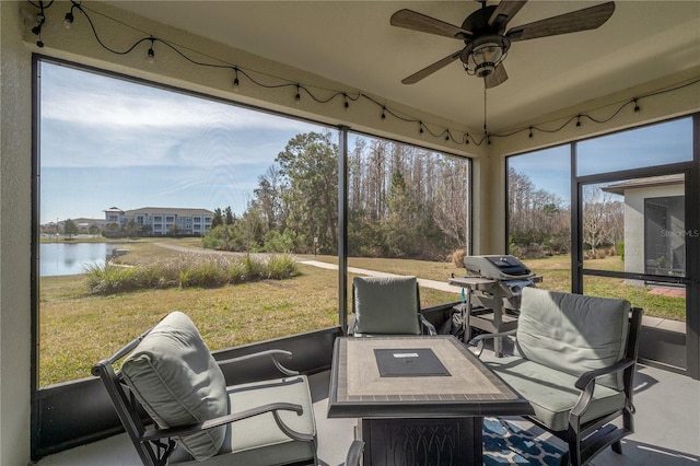 sunroom featuring a water view and ceiling fan