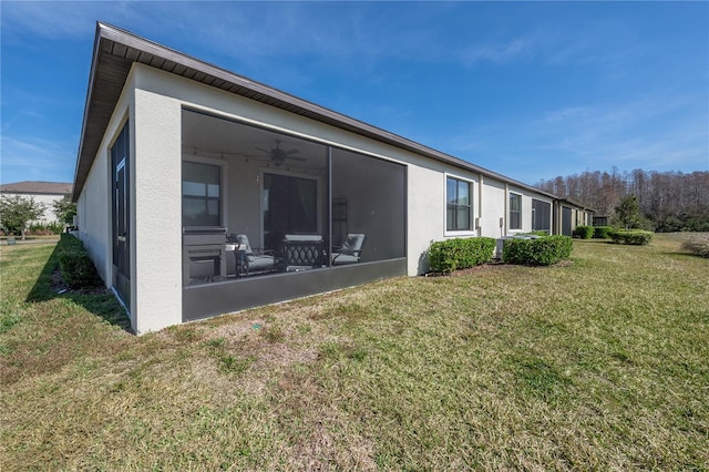 back of property with a yard, a sunroom, and ceiling fan