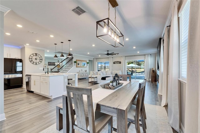 dining space with sink, crown molding, light hardwood / wood-style floors, and ceiling fan