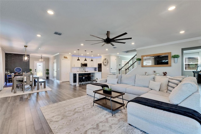 living room with ornamental molding, a wealth of natural light, and light hardwood / wood-style floors