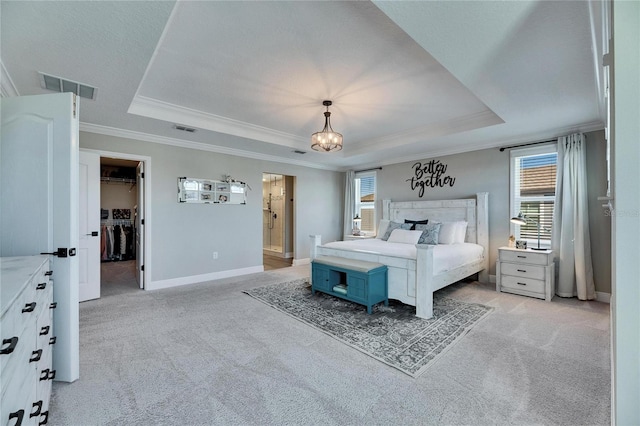 bedroom with a raised ceiling, ornamental molding, a walk in closet, and a closet