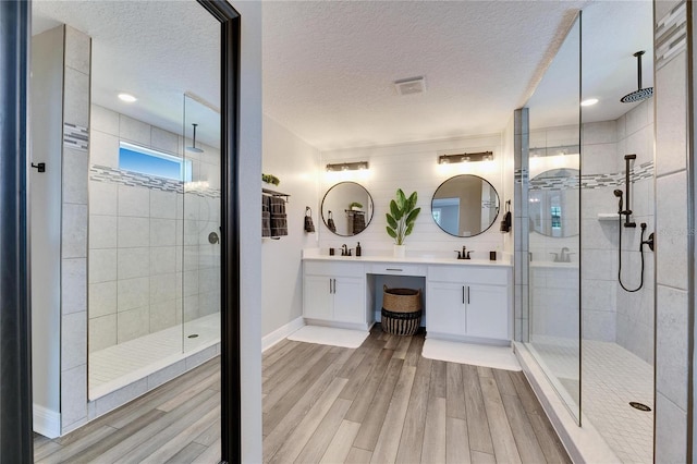 bathroom with hardwood / wood-style flooring, vanity, a textured ceiling, and a tile shower