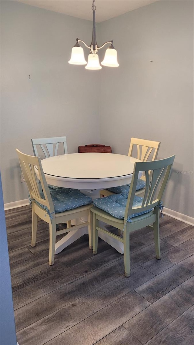 dining room with dark wood-type flooring and a chandelier