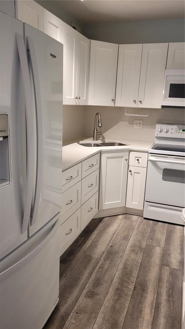 kitchen with dark hardwood / wood-style floors, sink, white cabinets, and white appliances