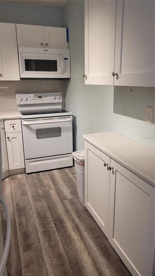 kitchen with white cabinetry, dark wood-type flooring, and white appliances