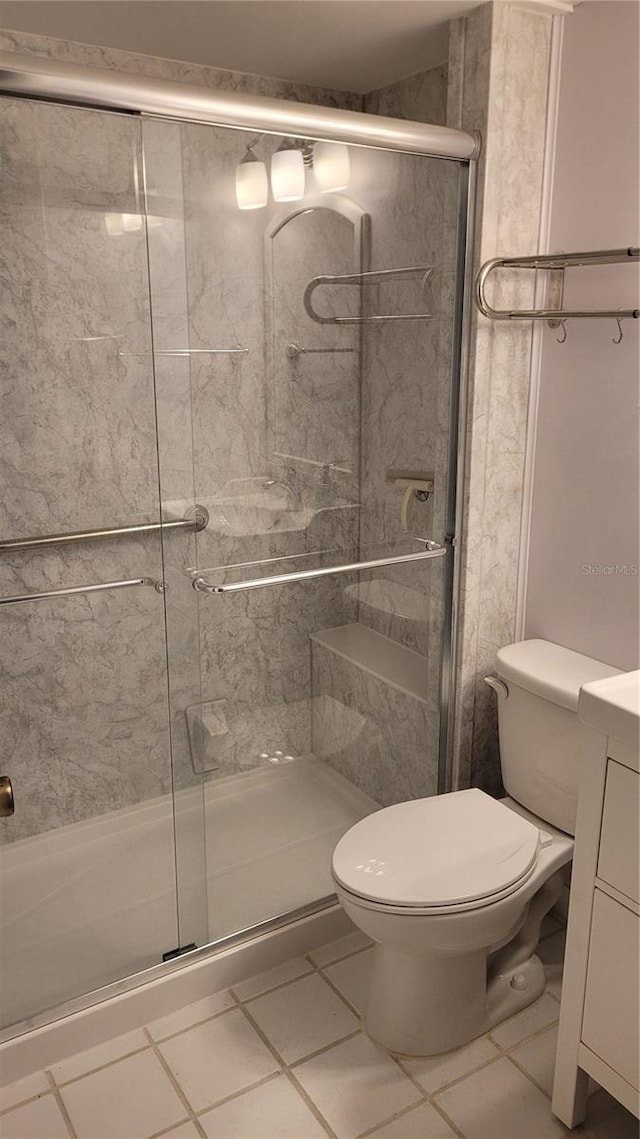 bathroom featuring tile patterned flooring, vanity, toilet, and a shower with shower door