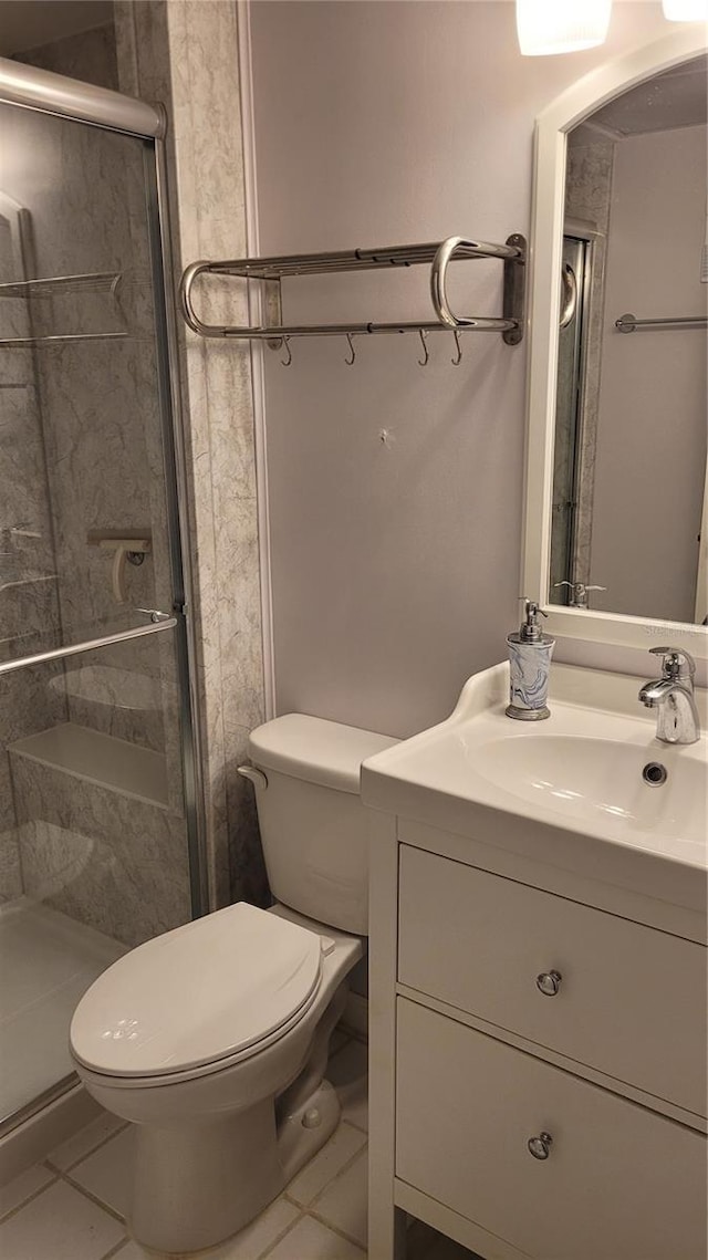 bathroom featuring tile patterned floors, vanity, toilet, and a shower with door