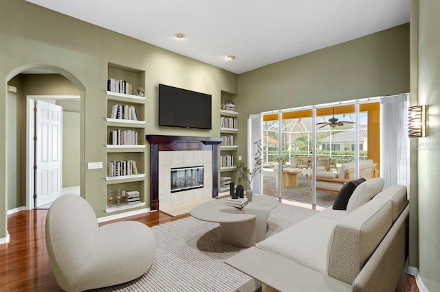 living room featuring wood-type flooring, a fireplace, and built in features