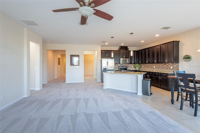 kitchen featuring appliances with stainless steel finishes, hanging light fixtures, a center island, tasteful backsplash, and dark brown cabinetry