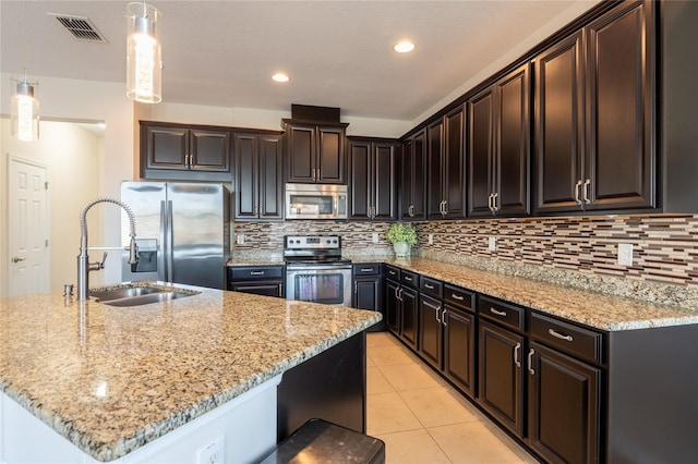 kitchen with appliances with stainless steel finishes, sink, hanging light fixtures, and a center island with sink