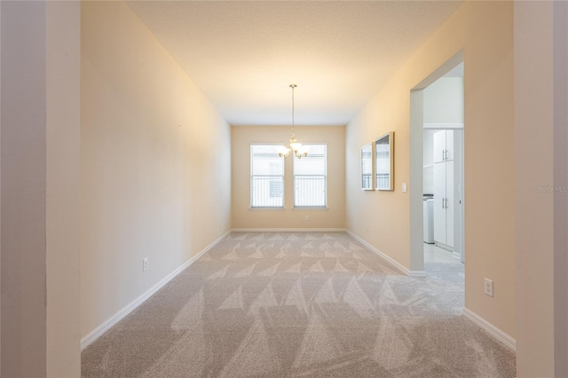 spare room with light colored carpet and a chandelier