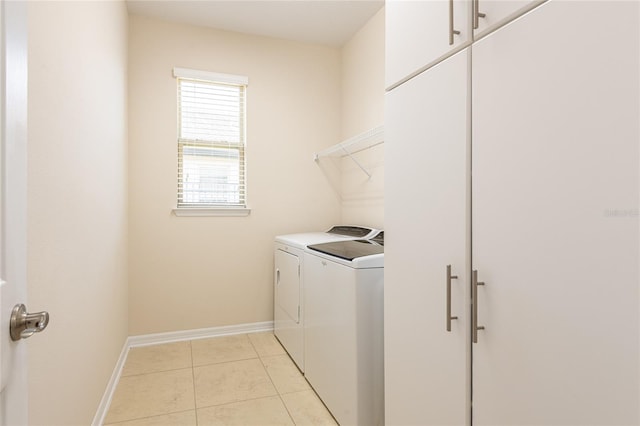 laundry area with cabinets, light tile patterned floors, and washing machine and clothes dryer