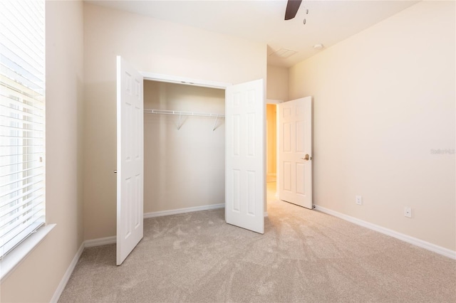 unfurnished bedroom with light colored carpet, a closet, and ceiling fan