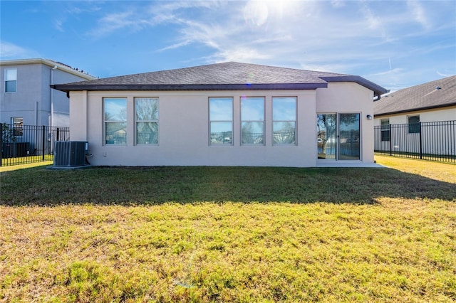 rear view of house with central AC unit and a lawn