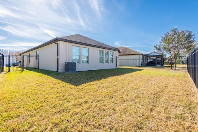 back of property with central AC unit and a lawn