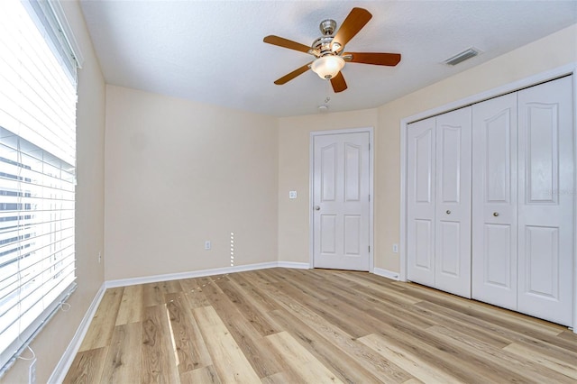 unfurnished bedroom with light hardwood / wood-style flooring, a closet, and ceiling fan