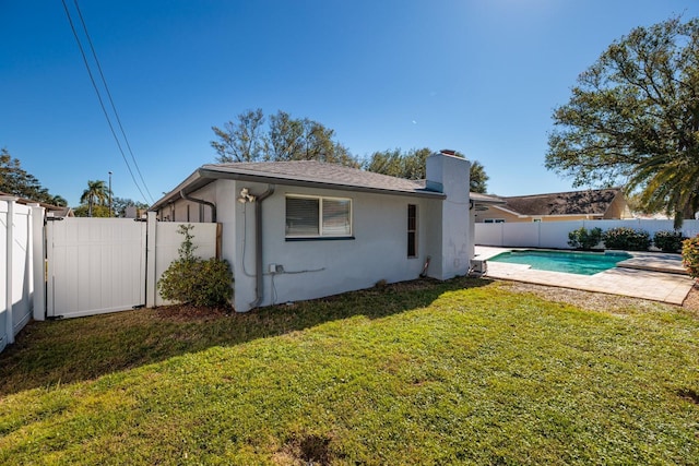 rear view of property with a fenced in pool, a yard, and a patio area