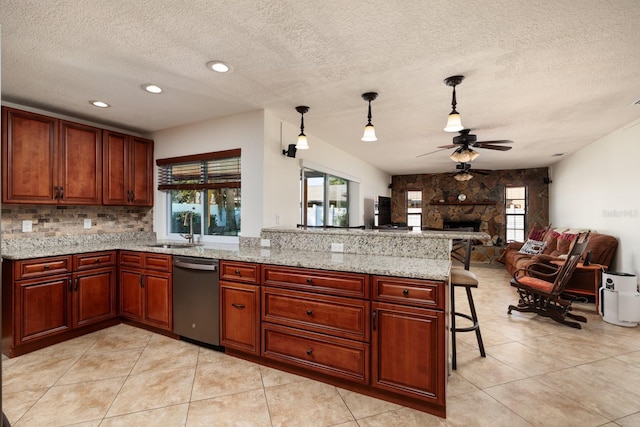 kitchen with pendant lighting, sink, a kitchen breakfast bar, light stone counters, and stainless steel dishwasher