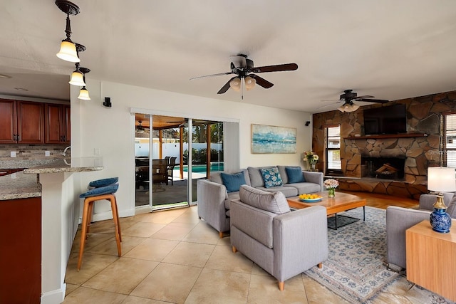 living room with light tile patterned flooring, ceiling fan, and a fireplace