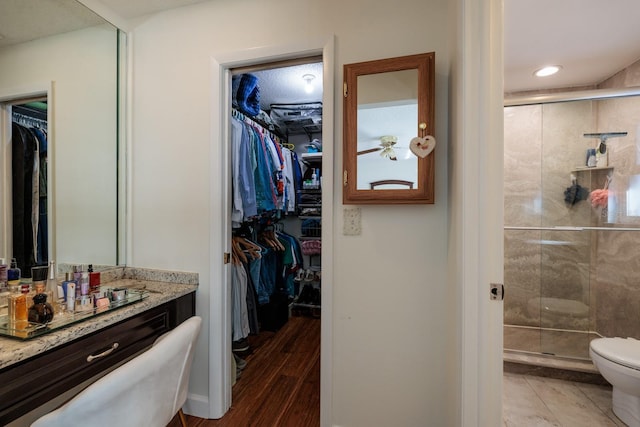 bathroom with toilet, hardwood / wood-style floors, vanity, and walk in shower