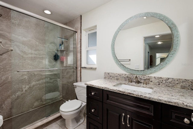 bathroom with a shower with door, vanity, tile patterned flooring, and toilet