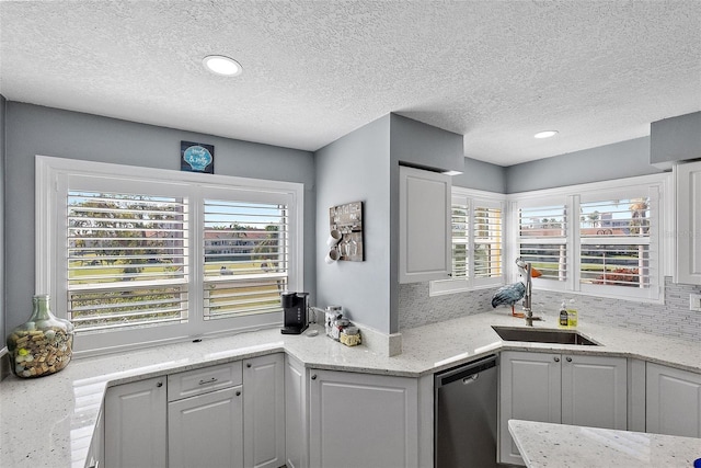 kitchen featuring tasteful backsplash, sink, white cabinets, stainless steel dishwasher, and light stone counters