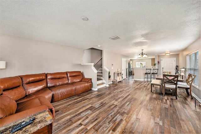 living room with an inviting chandelier, hardwood / wood-style floors, and a textured ceiling