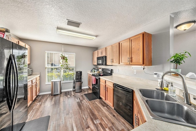 kitchen with decorative light fixtures, sink, dark hardwood / wood-style floors, and black appliances