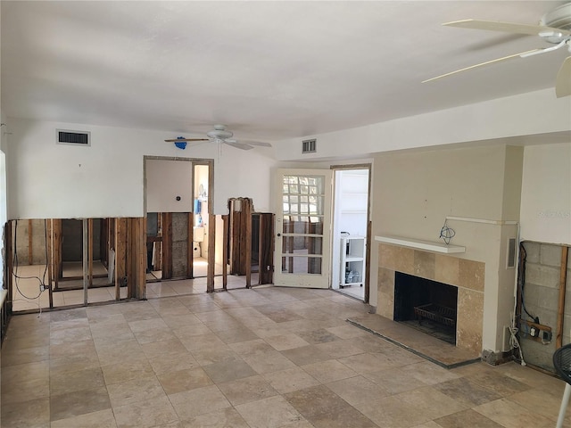 unfurnished living room with a tiled fireplace and ceiling fan