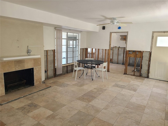 dining area featuring ceiling fan and a fireplace