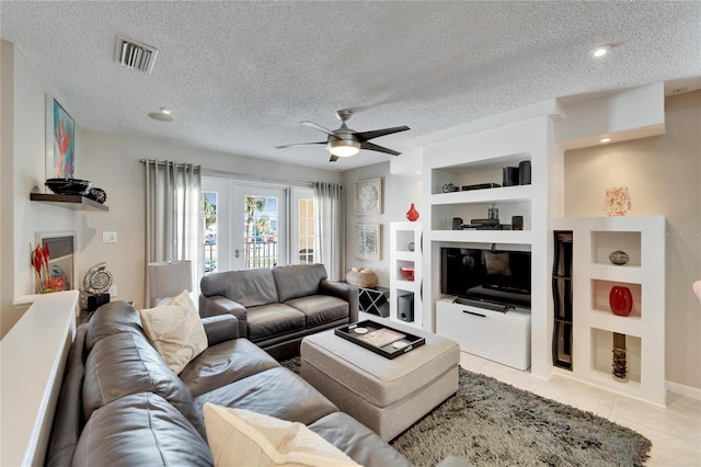 living room featuring ceiling fan, light tile patterned floors, built in features, and a textured ceiling