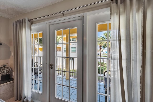 doorway to outside with a textured ceiling and french doors