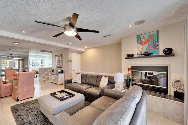 living room featuring ceiling fan, a textured ceiling, and light tile patterned floors