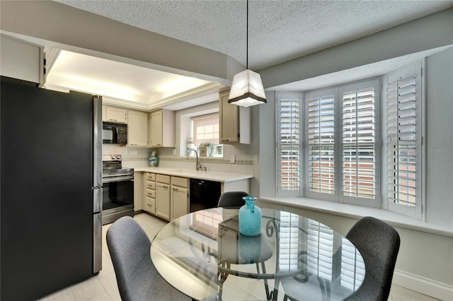 kitchen with sink, decorative light fixtures, black appliances, a textured ceiling, and cream cabinetry