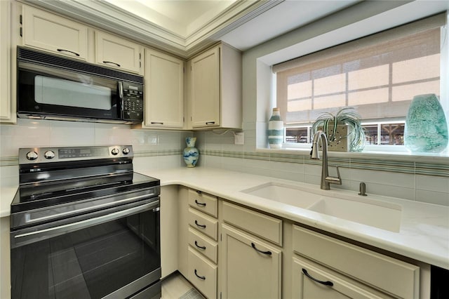 kitchen with tasteful backsplash, sink, stainless steel electric stove, and cream cabinetry