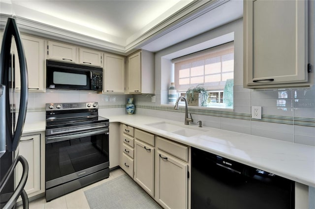 kitchen featuring tasteful backsplash, sink, black appliances, and cream cabinetry