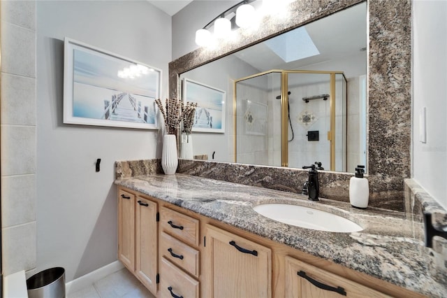 bathroom with vanity, tile patterned flooring, a skylight, and a shower with shower door