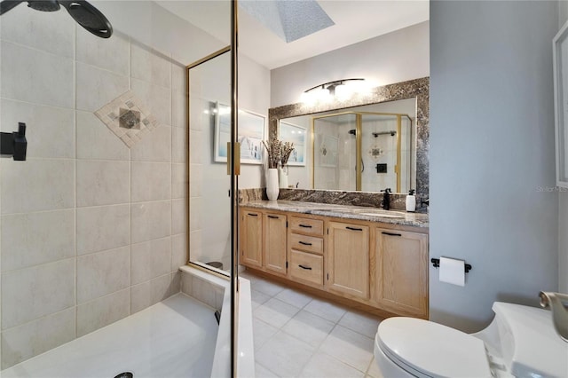 bathroom featuring vanity, tile patterned flooring, toilet, and tiled shower