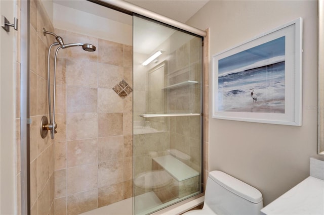 bathroom featuring a shower with door and toilet