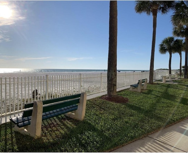 surrounding community with a water view, a view of the beach, and a lawn