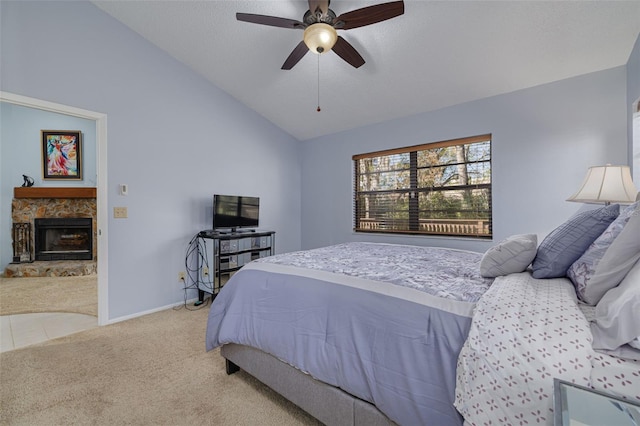 carpeted bedroom with ceiling fan, lofted ceiling, a stone fireplace, and a textured ceiling