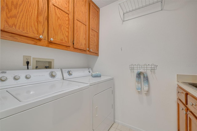 washroom with cabinets, washer and clothes dryer, and light tile patterned floors